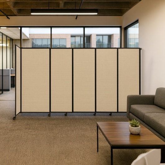 Beige folding room divider with black frame and wheels in a modern office lounge with a sofa and coffee table.