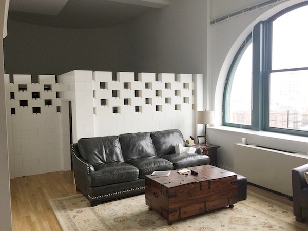 White modular partition wall with decorative openings dividing a living room