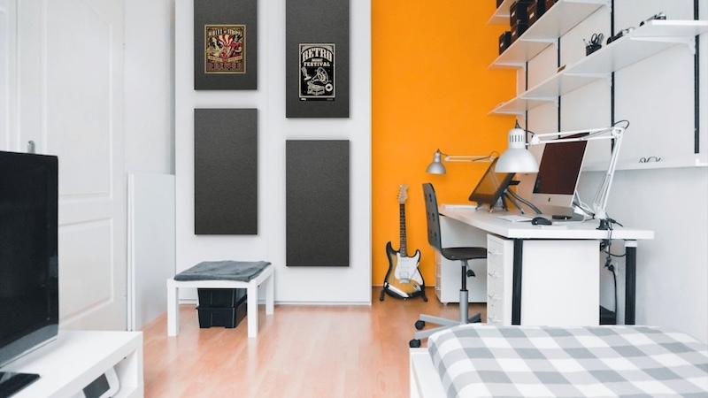 Modern home office with gray acoustic wall panels, a white desk, computer, and orange accent wall.