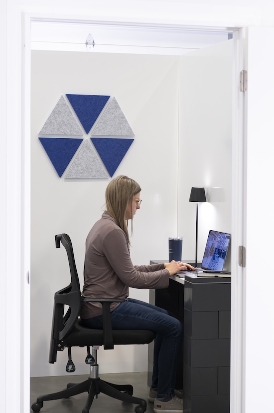 Woman working at a desk in a private EverPanel&reg; room with blue and gray SoundSorb&trade; acoustic wall panels